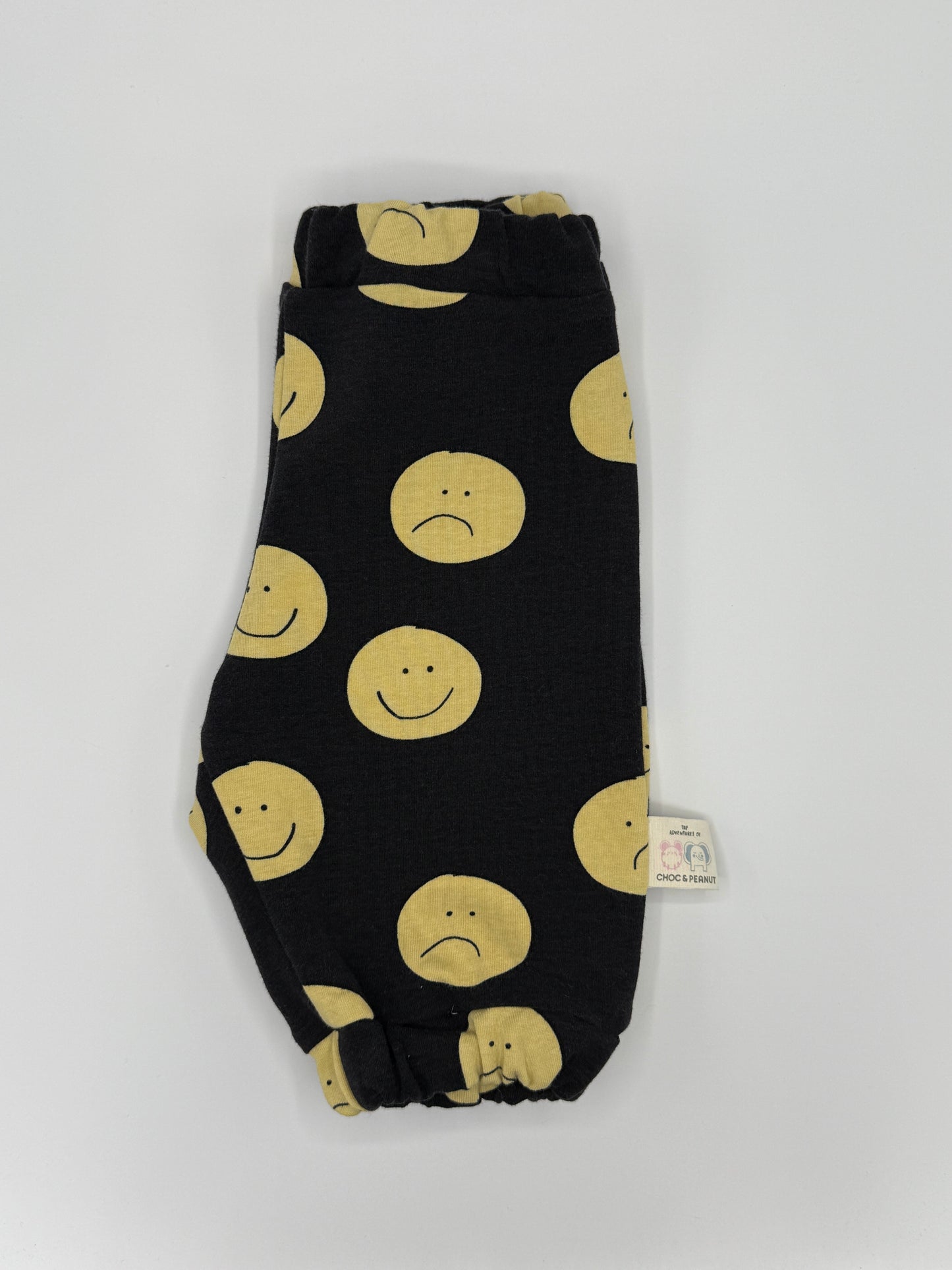 Black unisex sweatpants with yellow happy and sad faces. Elasticated waist and cuffs