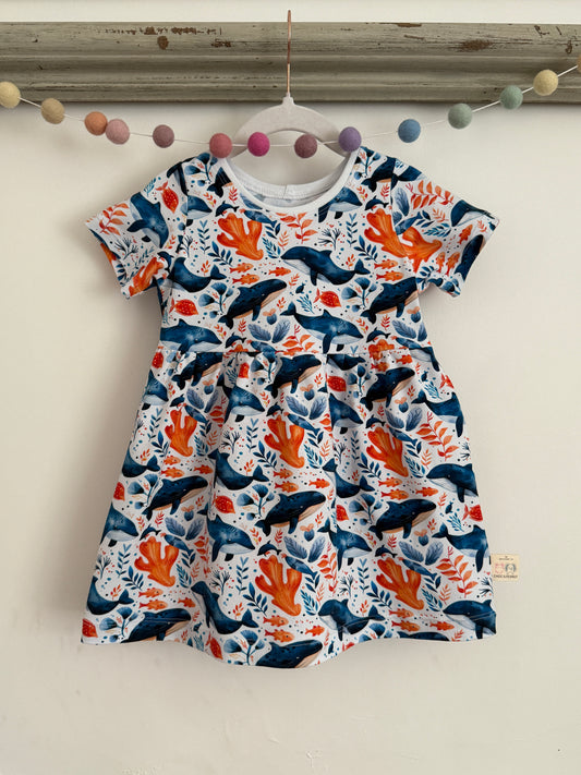 White stretchy girls dress with blue and orange whale, fish and sea plant print. Handmade from organic jersey