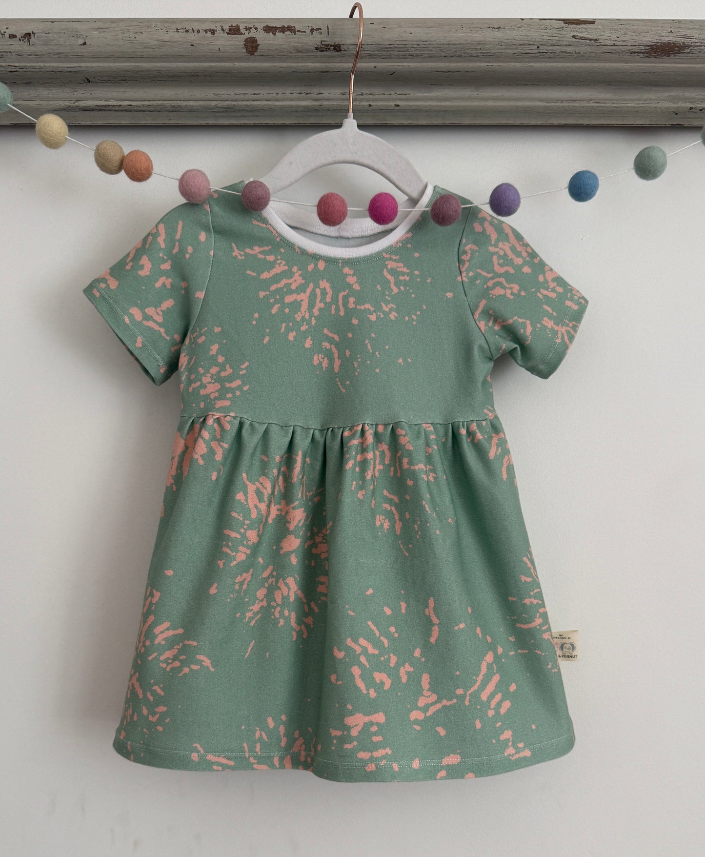 Green jersey stretchy kids dress with pink paint splats. Handmade of sustainable fabrics
