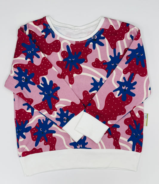 Unisex sustainable kids jumper with monster detail on a pink and purple background